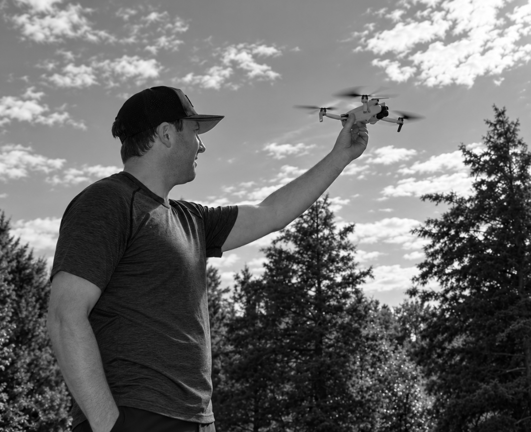 Man holding a drone in a field of trees