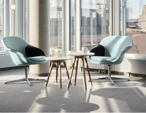 Two lounge chairs and small tables in a sunlit office